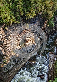 River running through deep gorge revealing many strata of sedimentary rock