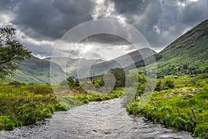River running trough beautiful Black Valley with dramatic sky and sun star, Ring of Kerry