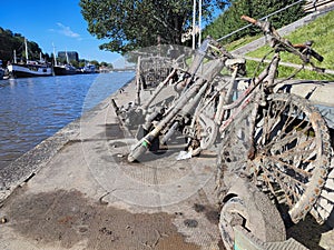River salvaged bicycles, scooters and trolleys are drying on a walkway.