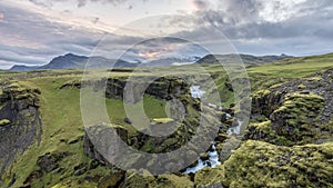 River Skogafoss meanders through crevices and green valleys beneath Icelandic glaciers.