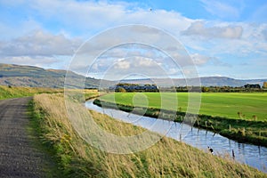 River stre train fields agriculture green blue skies long grass