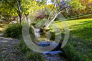 River-stream passing through Parque del Oeste, Madrid park with some autumn colors on a clear day in Madrid, Spain. photo