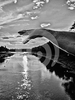 River sun reflection. Catch last sunbeam. Male hand pointing at sun in blue sky at evening time admire landscape