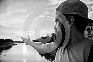 River sun reflection. Man in cap enjoy sunset while stand on bridge. Enjoy pleasant moment. Guy in front of blue sky at