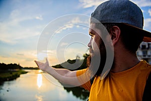 River sun reflection. Man in cap enjoy sunset while stand on bridge. Enjoy pleasant moment. Guy in front of blue sky at