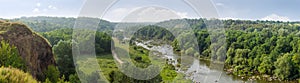 River valley with rapids, stones outcrops and hilly forested slopes