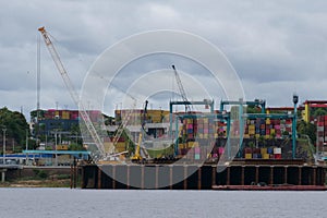 River view of the port of Manaus with a lot of colorful stacked containers and cranes. Location: Manaus, Brazil