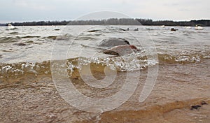 River wave on a sandy shore with two stones