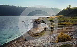 Riverbank with beach and grass on a cold morning in early spring