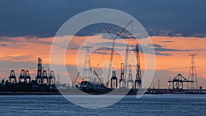 Riverbank with silhouettes of container terminal cranes during a sunset, Port of Antwerp, Belgium