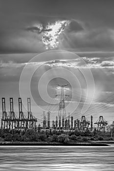 Riverbank with silhouettes of container terminal cranes during sunset, Port of Antwerp, Belgium