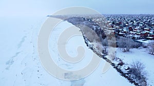 Riverbank in winter, drone view of the coastline and a large village. Save the planet. Winter concept.