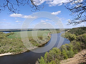 Riverbend in deep spring forestm with green trees on the bank of the river and sands under blue sky