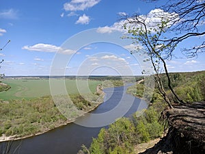 Riverbend in deep spring forestm with green trees on the bank of the river and sands under blue sky