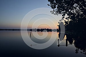 Riverside at sunset with its reflection casted in the water at sunset seen from afar