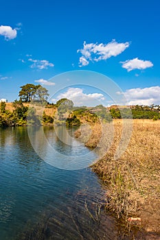 Riverside yellow grass countryside fields with bright blue sky at morning from flat angle