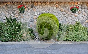 Riverstone wall with decorative bushes and hanging flower pot