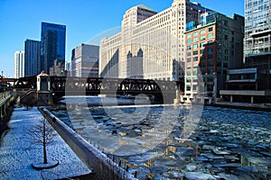 Riverwalk alongside a frozen Chicago River with ice chunks.