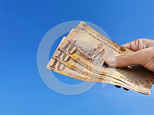 10 Riyal Saudi banknotes in hand against blue sky background. photo