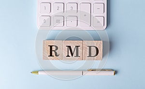 RMD word on wooden block with pen and calculator on blue background