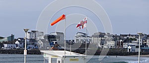 RNLI Flag and Orange windsock and Beach Warning Flags indicating sea hazard on sandy beach in UK