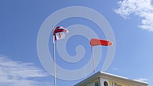 RNLI Flag and Orange windsock and Beach Warning Flags indicating sea hazard on sandy beach in UK