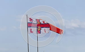 RNLI Flag and Orange windsock and Beach Warning Flags indicating sea hazard on sandy beach in UK