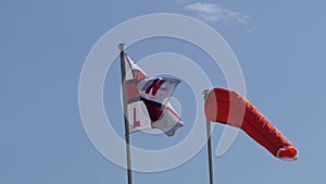 RNLI Flag and Orange windsock with Beach Warning Flags indicating sea hazard on a sandy beach in UK