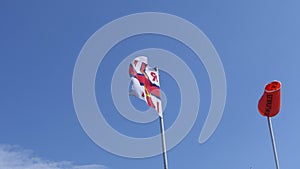 RNLI Flag and Orange windsock with Beach Warning Flags indicating sea hazard on a sandy beach in UK