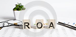 ROA Return on Asset acronym on wooden cubes on, WHITE background. Business concept