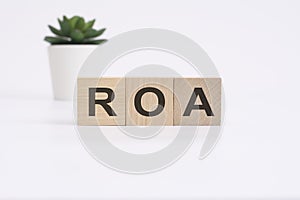 ROA - Return on Asset - acronym on wooden cubes on white background. business concept
