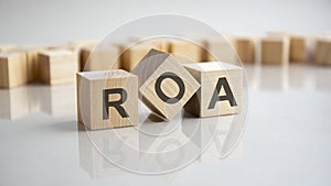 ROA - Return On Assets acronym concept on cubes, gray background