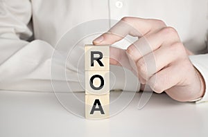 roa - return on assets acronym, wooden blocks, business concept gray background, financial document