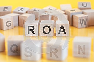 ROA - return on assets - acronym on wooden cubes on yellow background. concept