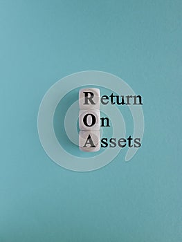 ROA- return on assets symbol. Wooden cubes with the inscription return on assets on beautiful blue background. Business concept.