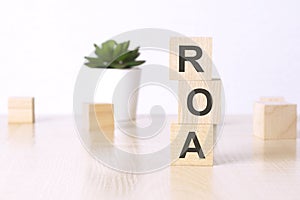 roa - Return On Assets. wooden cubes and flower in a pot on background