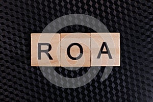 ROA Return On Assets from wooden letters on a black background