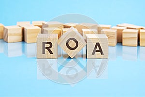 ROA text is made of wooden building blocks lying on the bright blue table, concept