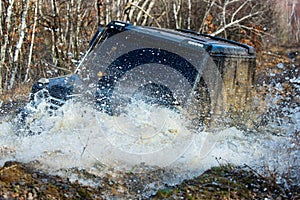 Road adventure. Water splash in off-road racing. Safari. Car racing offroad. Fragment of offroad car stuck in dirt close