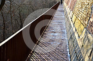 Road along the baroque bastion. modern railing made of corten sheet metal. The sidewalk is paved with burnt bricks. the high wall