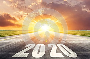 Road asphalt road with the inscription 2020 year with the rising sun in the morning. The concept of the beginning of new goals and