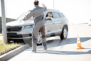 Road assistance worker helping to drive for a young woman