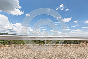 Road and barrier at with blue sky background and raincloud moving in the afternoon sunlight