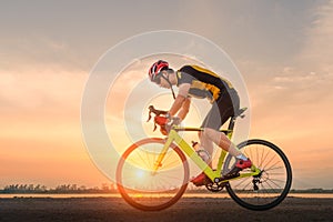 Road bike cyclist man cycling. Biking sports fitness athlete riding bike on an open road to the sunset.