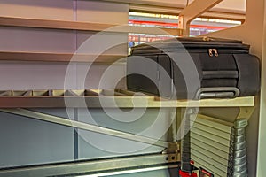 Road black suitcase on shelf in high-speed train. Concept of train travel and cargo transportation. Holiday background.
