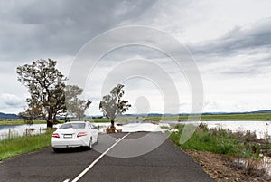 Road blocked by deep floodwater runoff from a field car unable to pass