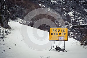Road blocked sign on snow covered mountain road in Corsica