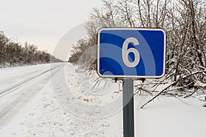 Road blue sign in winter forest, sixth kilometer