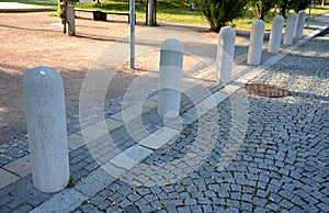 Road bollard as a barrier against cars driving into the pedestrian zone or city park separated from the road by cubes by light