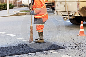 A road builder collects fresh asphalt on part of the road and levels it for repair in road construction